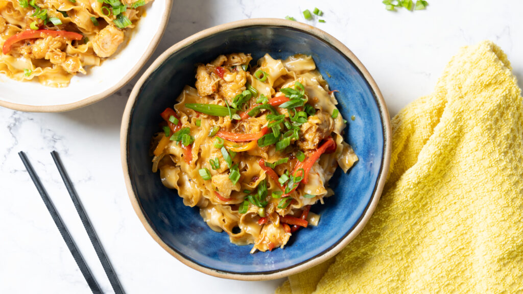 Sticky garlic chicken noodles topped with sesame seeds and green onions